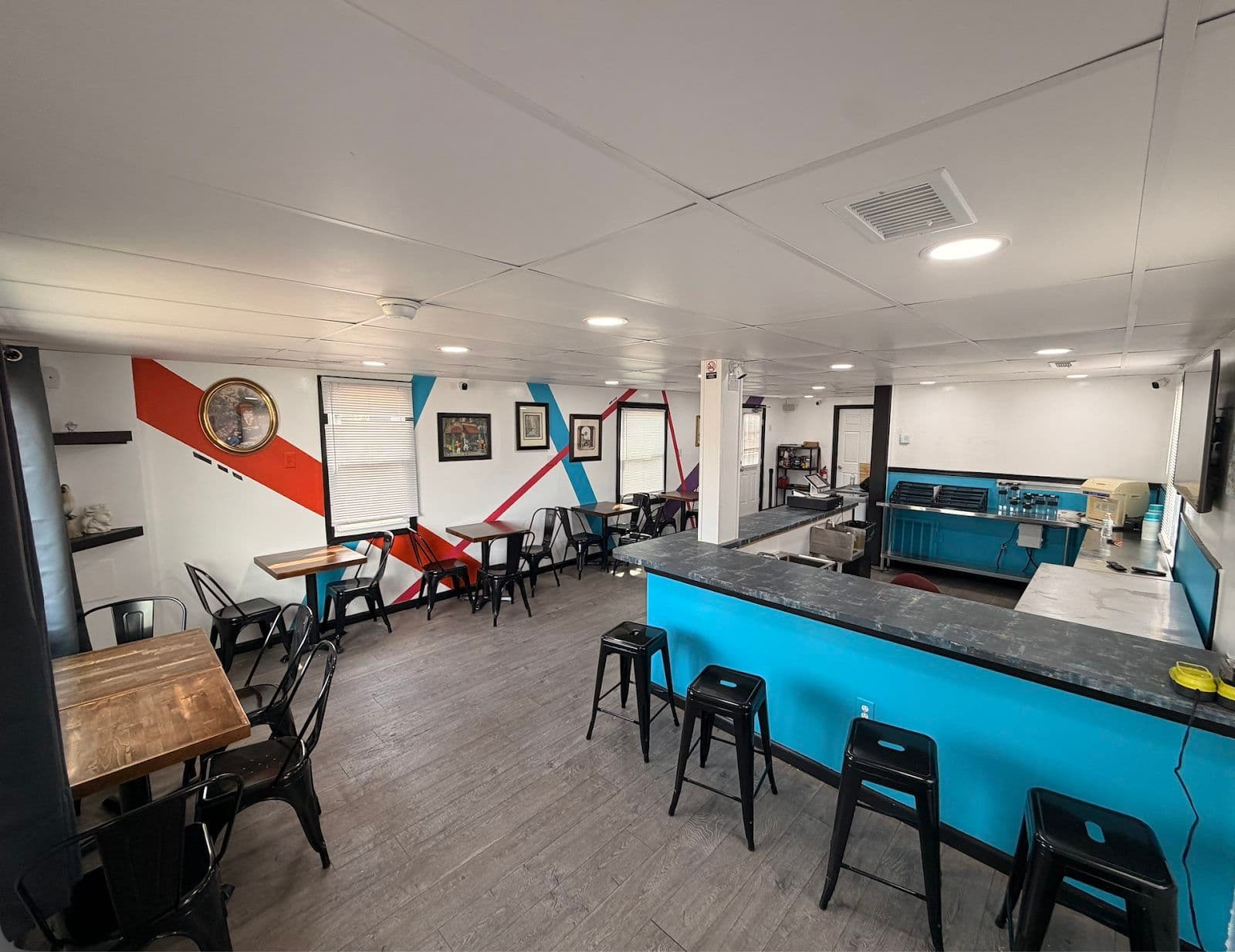 Indoor seating area at Just Chillin with tables, stools, and the striped accent wall