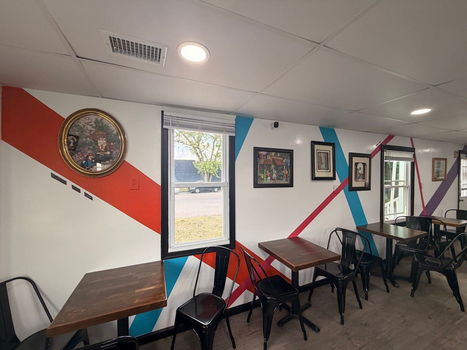 A cozy seating nook at Just Chillin with wooden tables, black chairs, and framed art