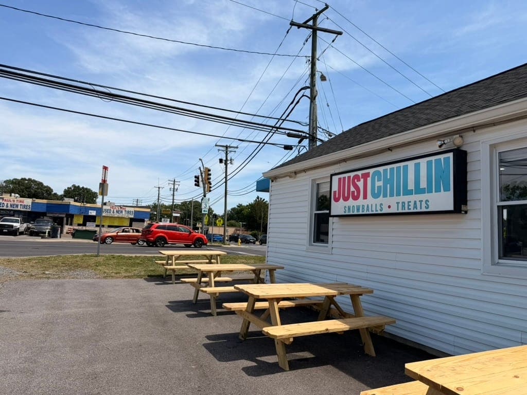 Wooden picnic tables on the patio beside the Just Chillin sign, along Crain Highway