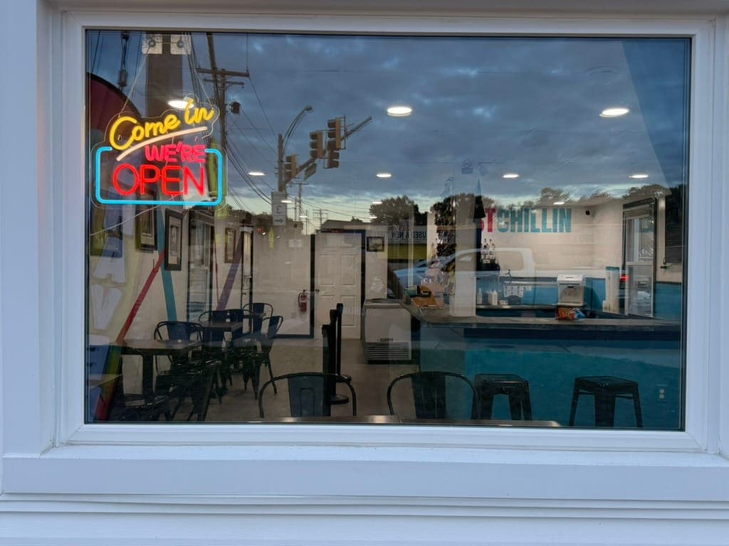 The 'Come in, we're open' neon sign glowing in the front window at Just Chillin