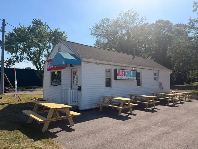 Just Chillin storefront with a row of picnic tables set up outside